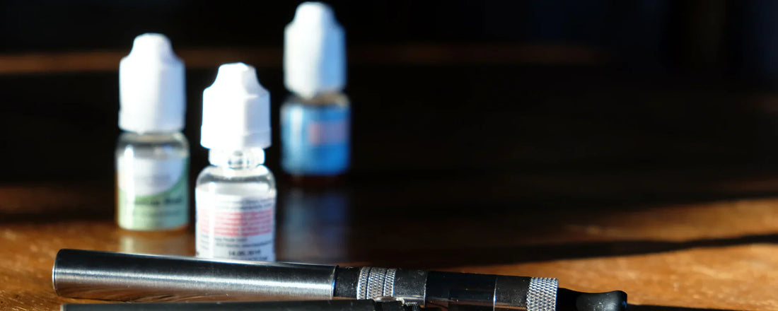 CBD booster shots with a vape device on a wooden table