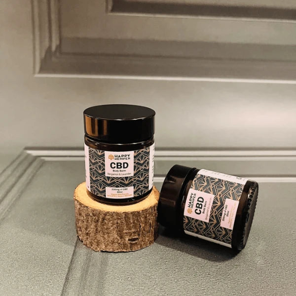 Happy Hemper 200mg Body Balm on a chopped, wood log | The CBD Hut