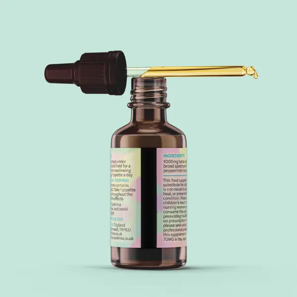 Rebelicious CBD oil dropper bottle with a gold applicator on a light blue background | The CBD Hut