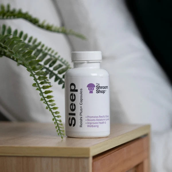 Bottle of 'Sleep' capsules from The Shroom Shop on a wooden surface with a blurred background | The CBD Hut