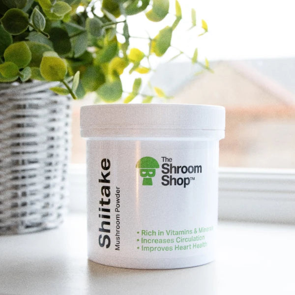 Shiitake mushroom powder container from The Shroom Shop on a white surface with a blurred plant in the background | The CBD Hut