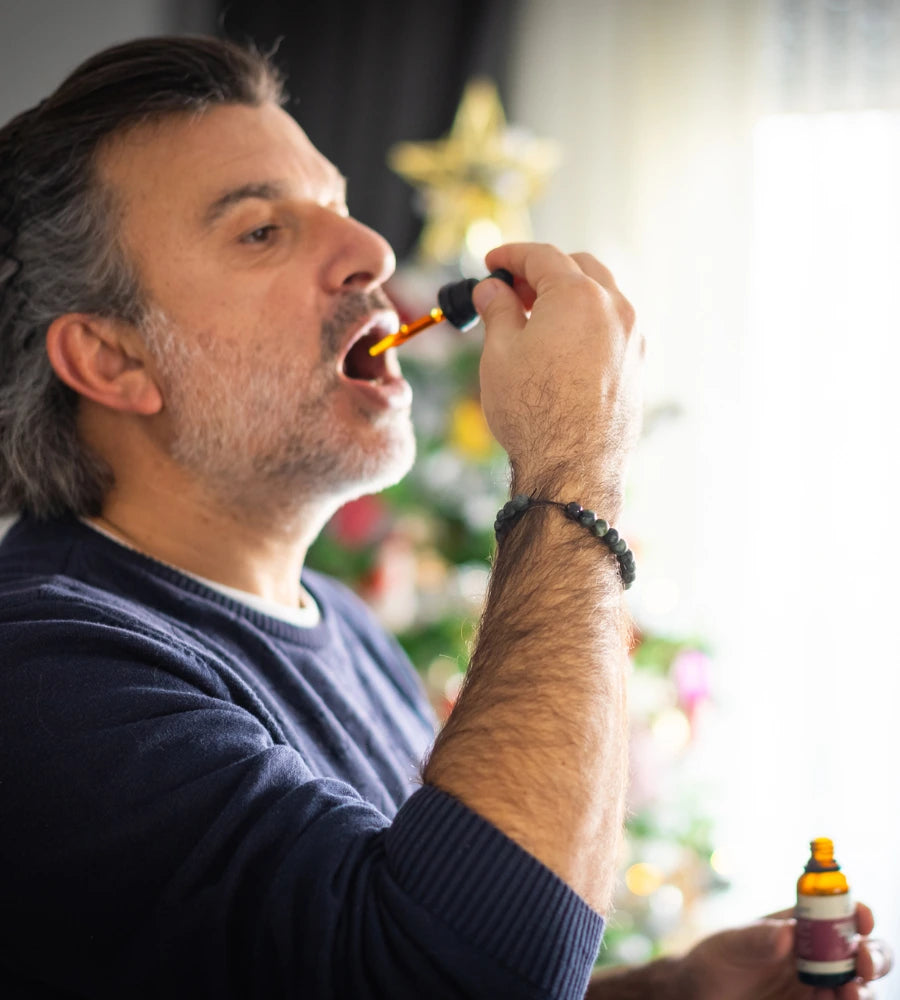 Older man taking CBD oil drops orally to assist with his medical condition | The CBD Hut