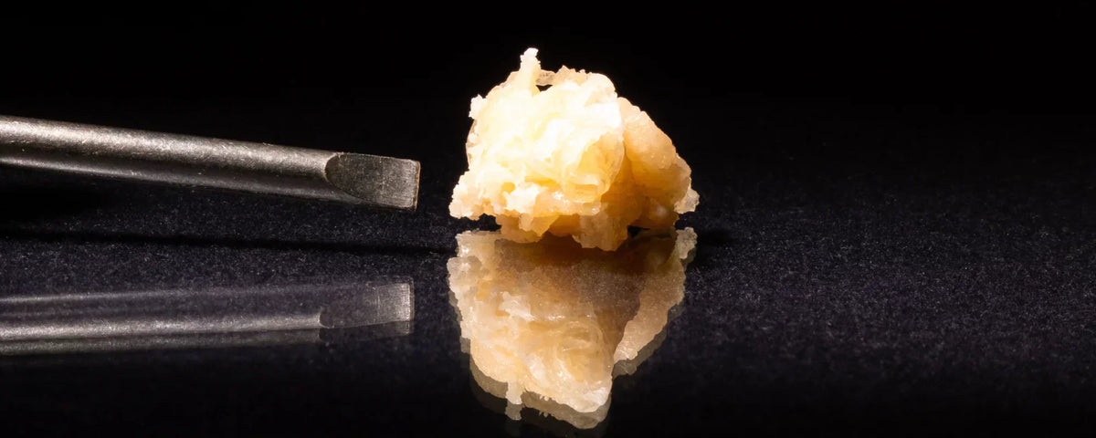 CBD crumble with a dabbing tool on a dark, black table top