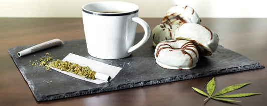CBD-infused treats including CBD tea & chocolate biscuits with a CBD joint laying on a granite slate tile