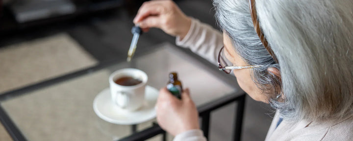 Senior woman adding CBD oil to her cup of tea