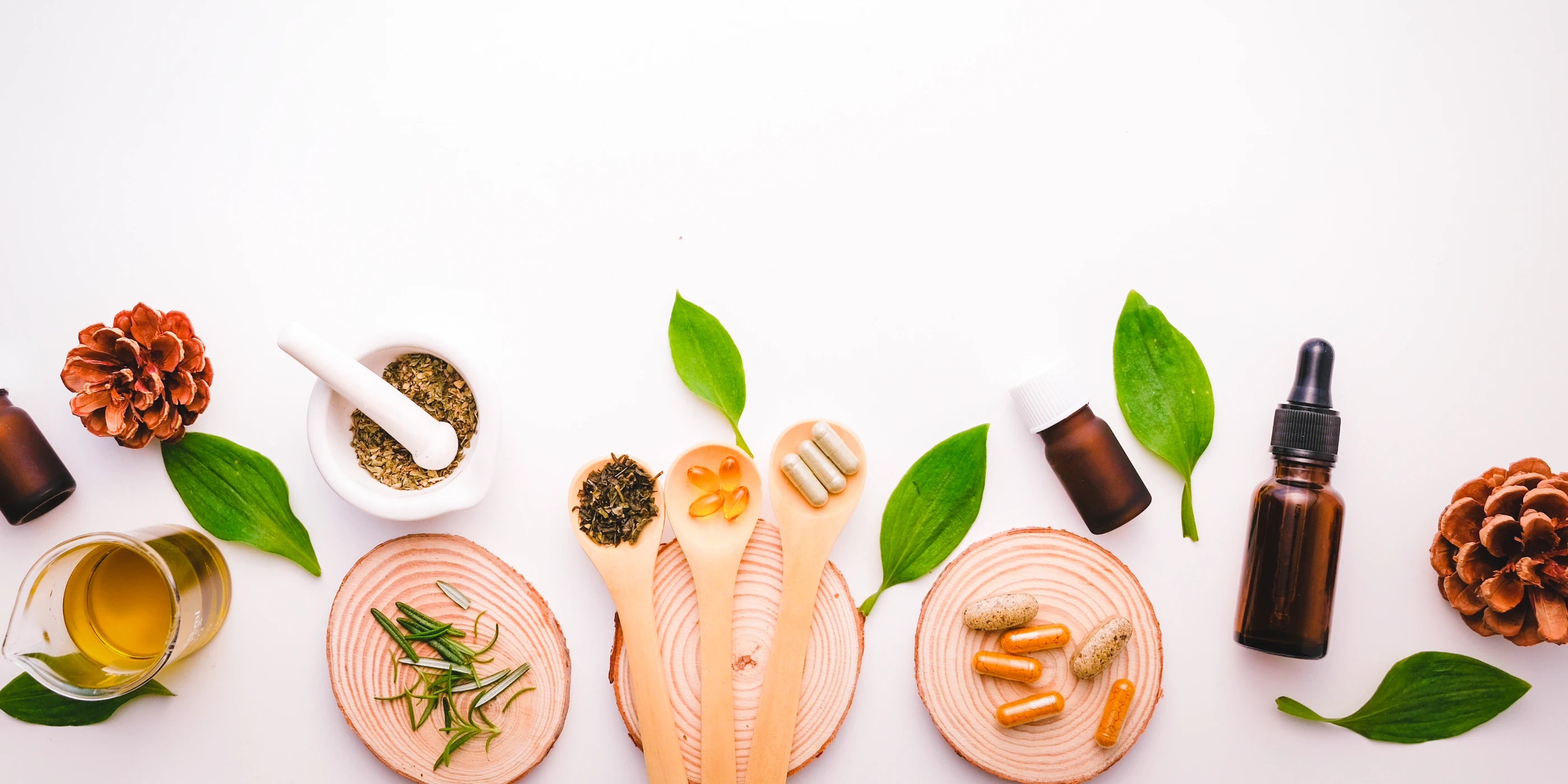 Herbal and natural products including bottles, leaves, and wooden tools on a white background
