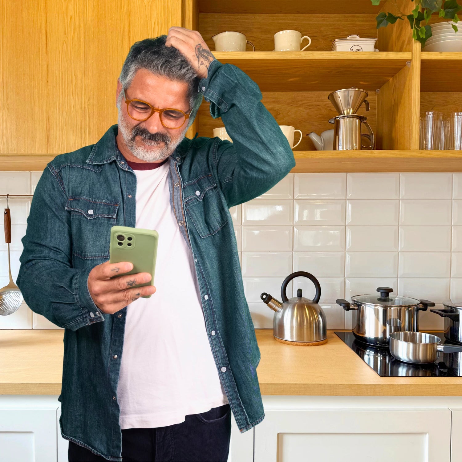 Man in a kitchen using a smartphone with a coffee setup in the background