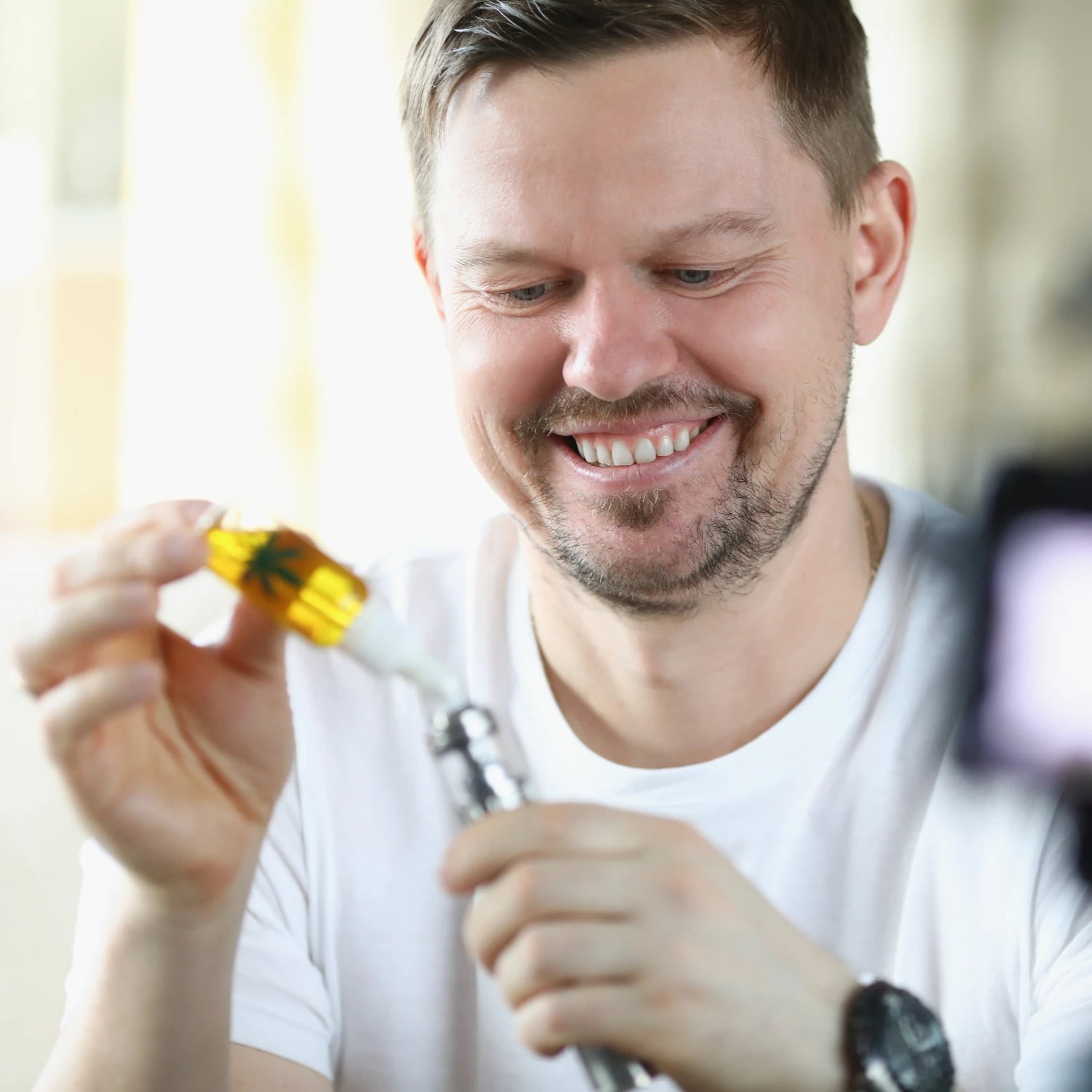 Man adding CBD vape liquid to a vape pen with a blurred background