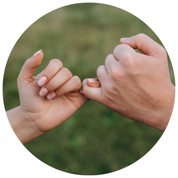 Two hands holding each other with a blurred green background