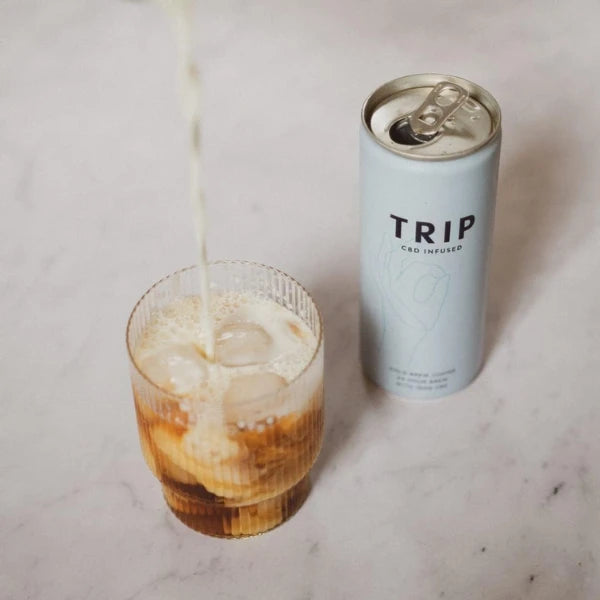 Can of TRIP Cold Coffee drink being poured into a glass with a drink on a marble surface | The CBD Hut
