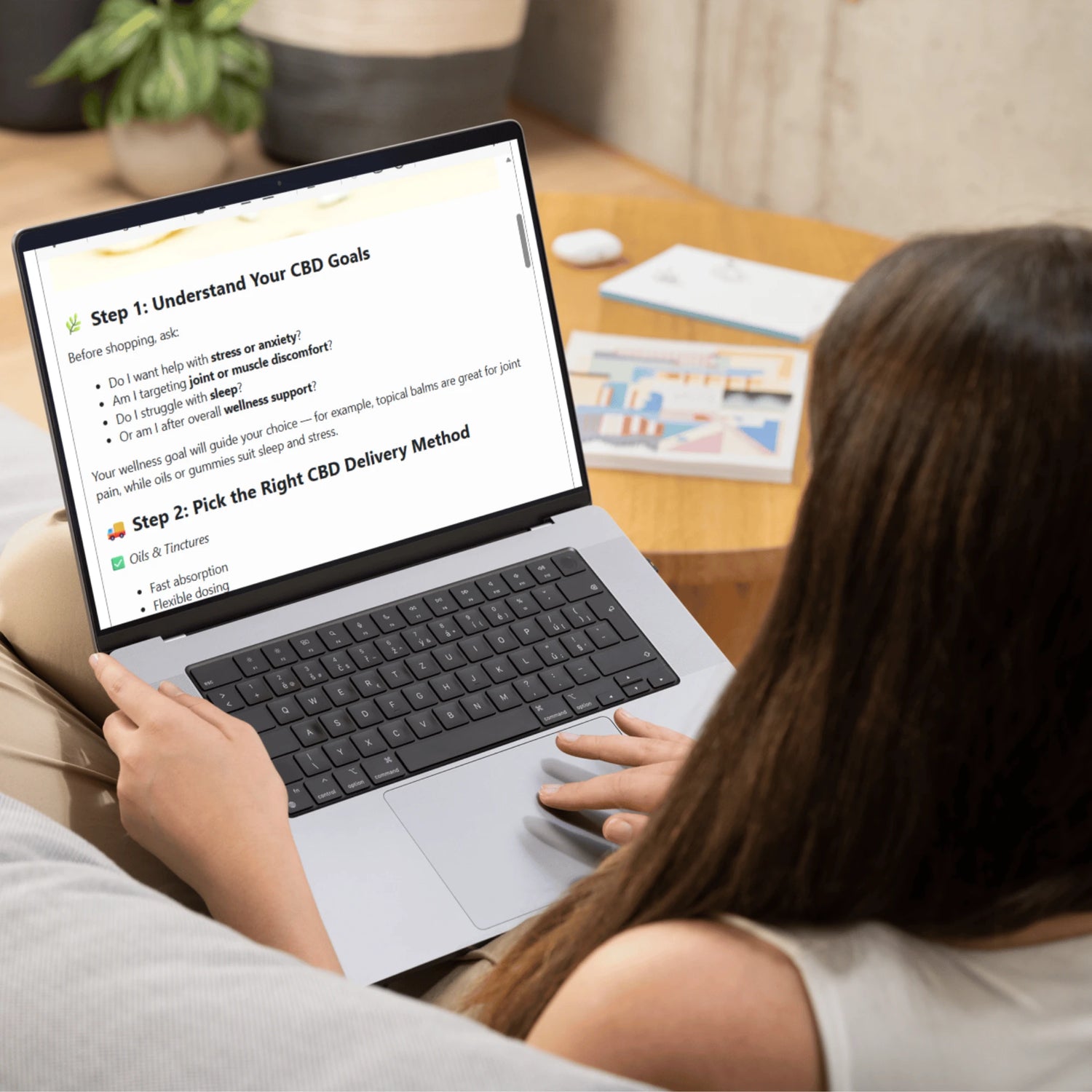Person using a laptop with a CBD education screen on a wooden table.