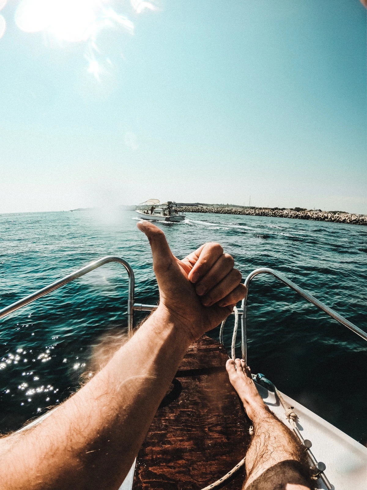 Man holding his thumb up whilst sailing on a boat in the ocean