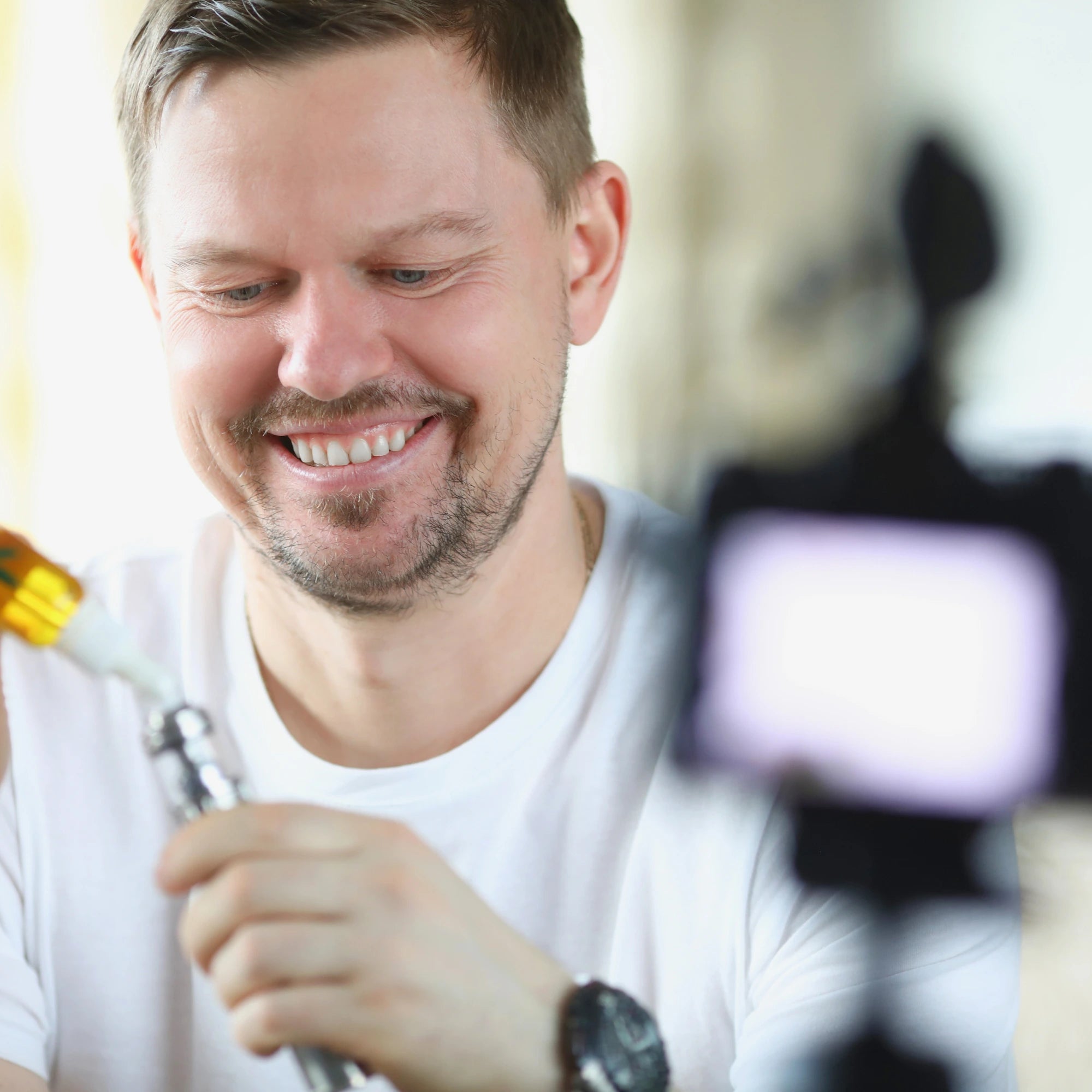 Man adding CBD vape liquid to a vape pen with a blurred camera in the foreground